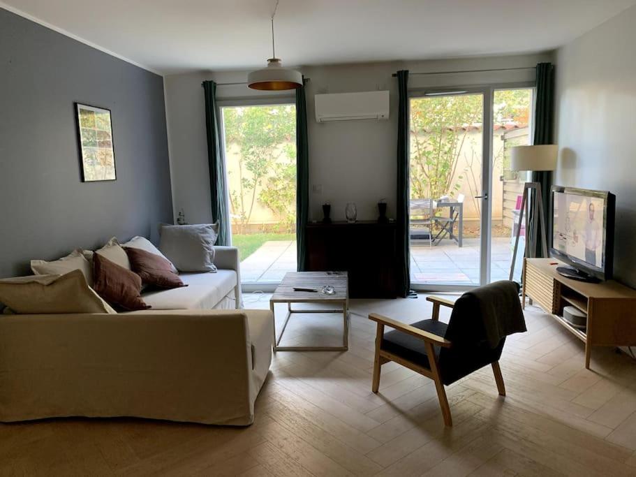 een woonkamer met een witte bank en een stoel bij Appartement très calme avec jardin plein sud in Lyon