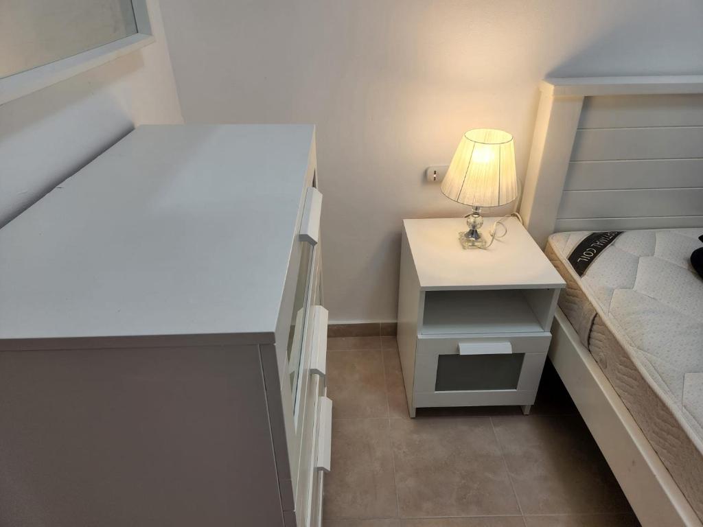 a small bedroom with a bed and a table with a lamp at city holiday in Rishon LeẔiyyon