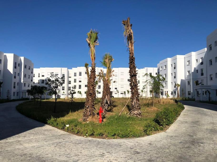 ein Gebäude mit Palmen und einem roten Hydranten in der Unterkunft Superbe Appartement meuble Alliance Darna Tanger in Tangier
