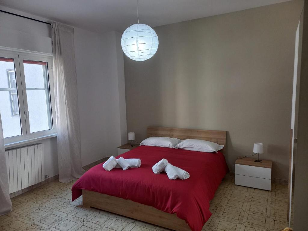 een slaapkamer met een rood bed en handdoeken erop bij La finestra sul cortile in Castellaneta