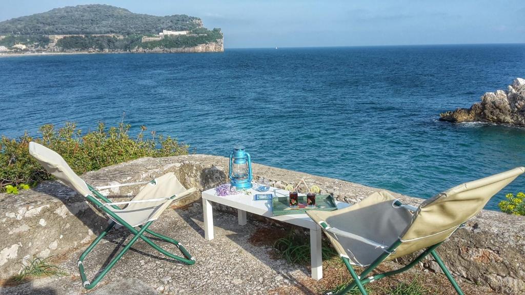 a table and two chairs sitting on a wall near the water at Gaeta Villino Isabella in Gaeta