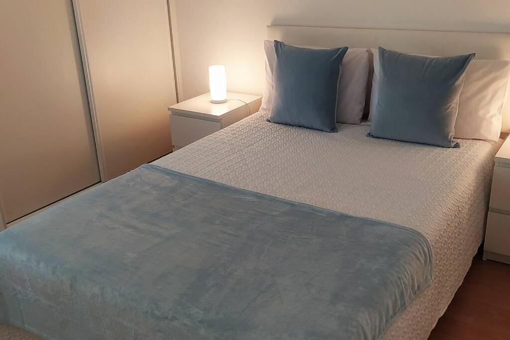 Hotel Lisboa/City/Sunny Apar/Metro/Airport/WiFi/Air Cond, a bedroom with a large bed with blue pillows at Lisboa/City/Sunny Apar/Metro/Airport/WiFi/Air Cond in Lisbon