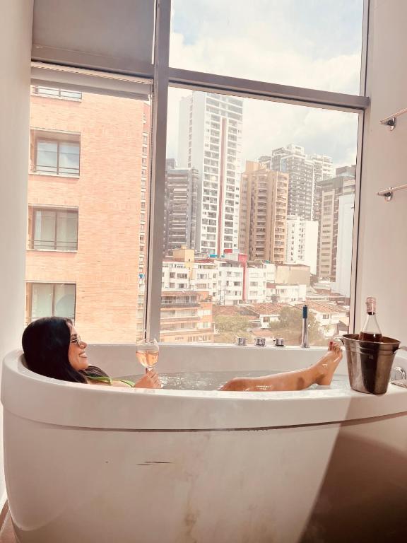 una mujer acostada en una bañera con una copa de vino en BGA Hotel, en Bucaramanga