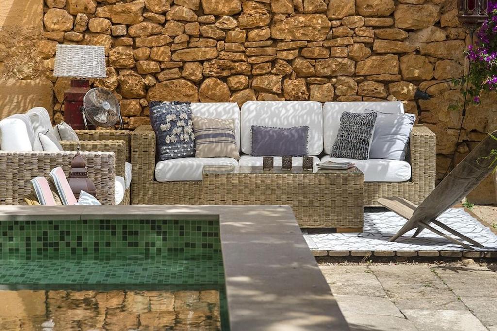 a white couch sitting in front of a stone wall at Ca Na Mon in Ses Salines