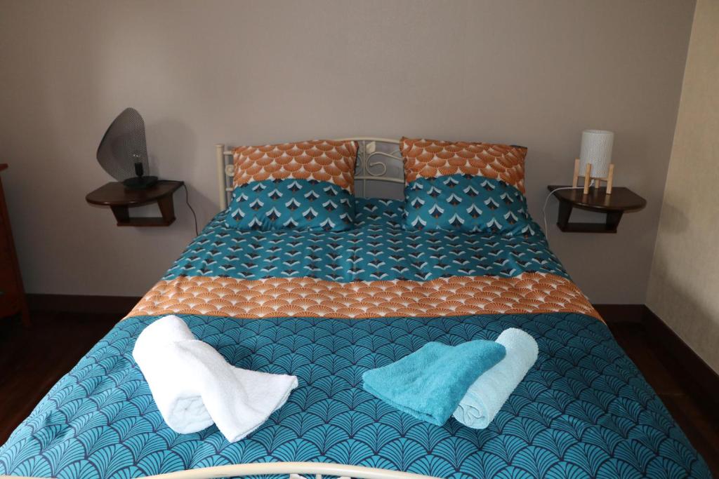 Una cama con dos manoplas y toallas. en CHAMBRES D'HÔTES AU DETOUR DU MONT St Michel en Roz-sur-Couesnon