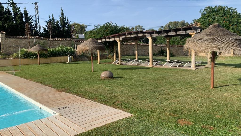 a backyard with a swimming pool and umbrellas at Hotel Nómadas in Vejer de la Frontera