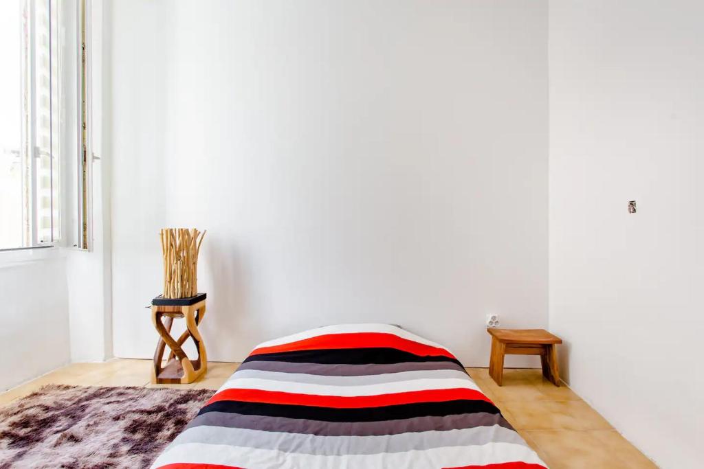 une chambre avec un lit avec une couverture rayée dans l'établissement Room rental in apartment in Marseille, à Marseille