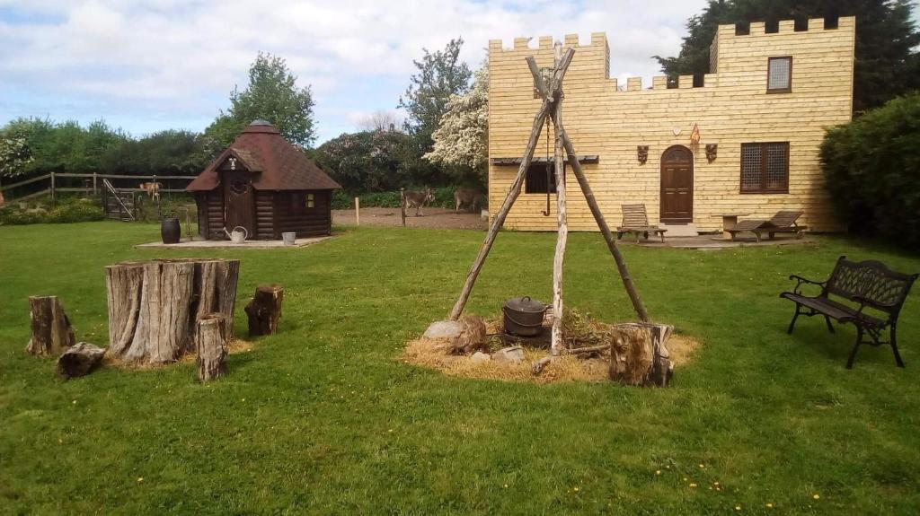 a yard with a building and a bench in the grass at Ecuries Leseigneur - Camping Insolites in Bolleville