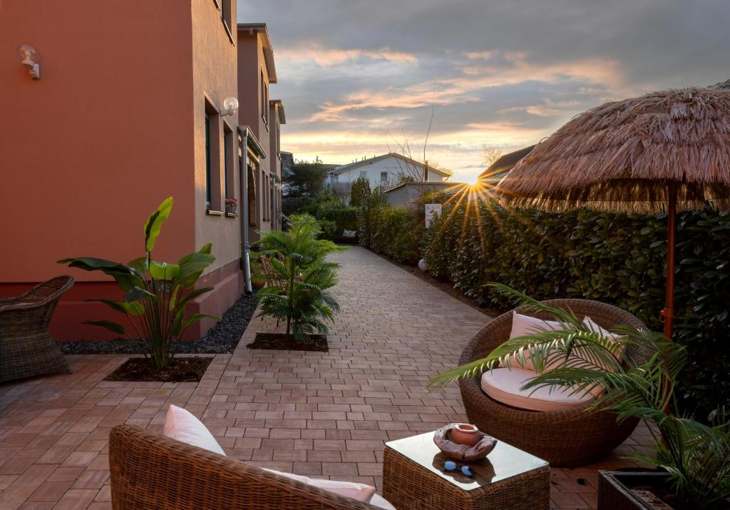 eine Terrasse mit Stühlen, einem Sonnenschirm und einem Sonnenuntergang in der Unterkunft Pension Lavida Usedom in Zinnowitz