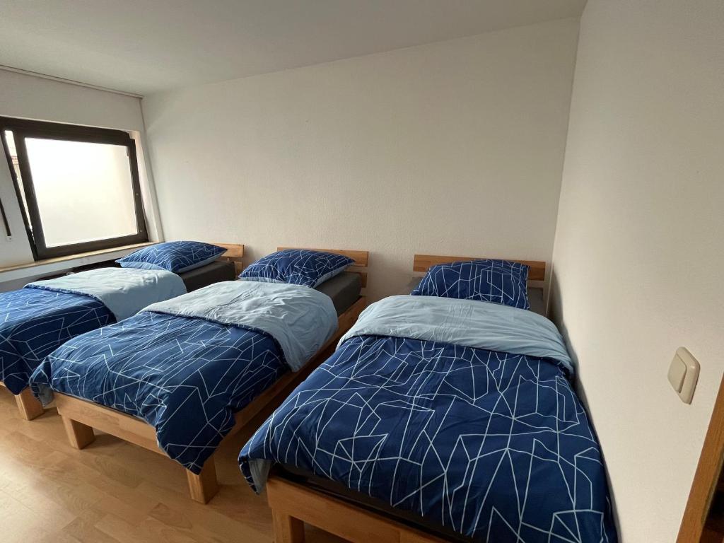 a bedroom with three beds with blue comforters and a window at Apartment Essen in Essen