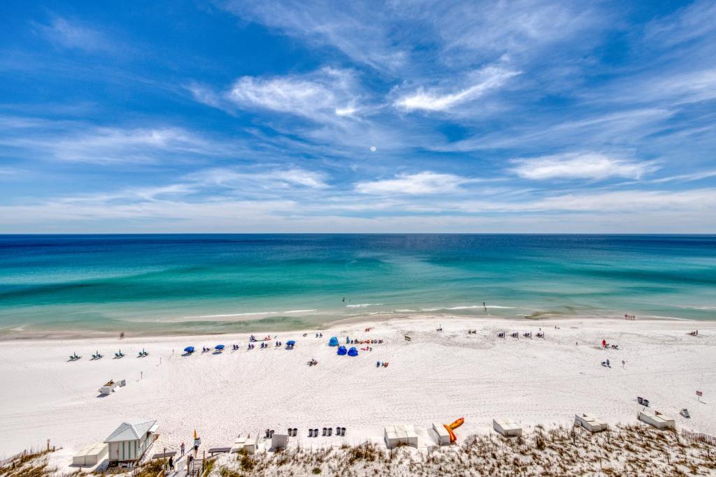 a beach with a group of people and the ocean at Pelican Beach Resort 1205 in Destin