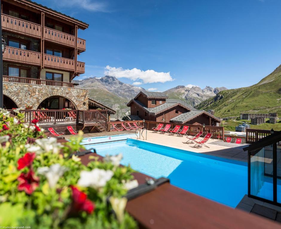 um resort com piscina e montanhas ao fundo em Hôtel Village Montana by Les Etincelles em Tignes