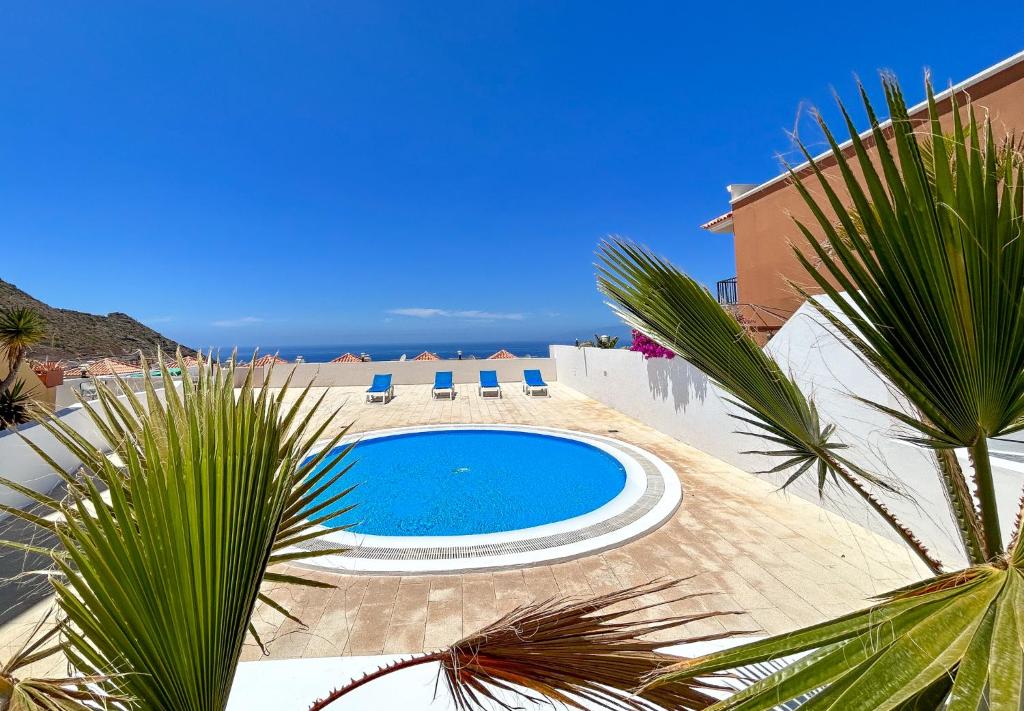 a swimming pool with chairs and a palm tree at Roque del Conde Seaview in Adeje