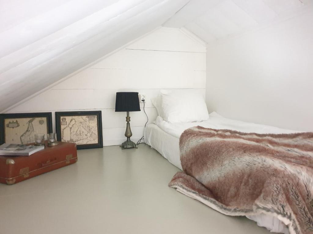 1 dormitorio blanco con 1 cama y 1 maleta en Sönerna på Nordgrenska semesterboende 12B, en Åmål