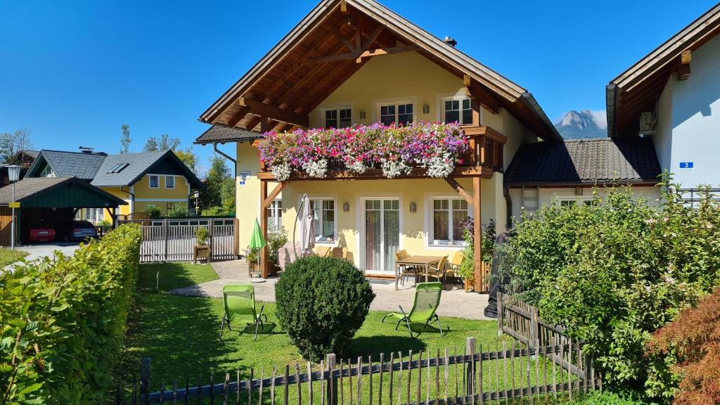 a yellow house with flowers in a yard at Ferienhaus Pepi in Strobl