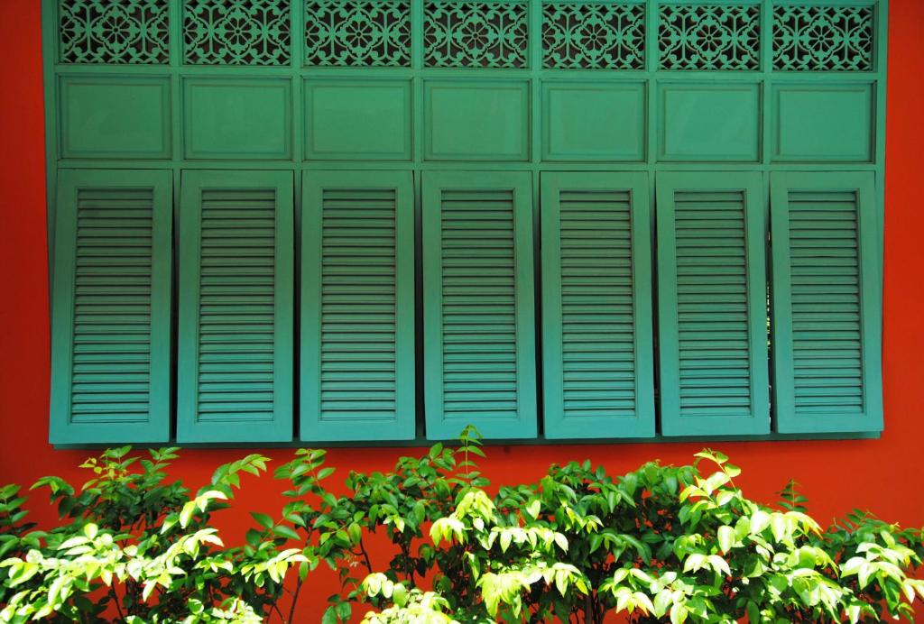 a green window on a red wall with a bush at Focal Local Bed & Breakfast in Bangkok