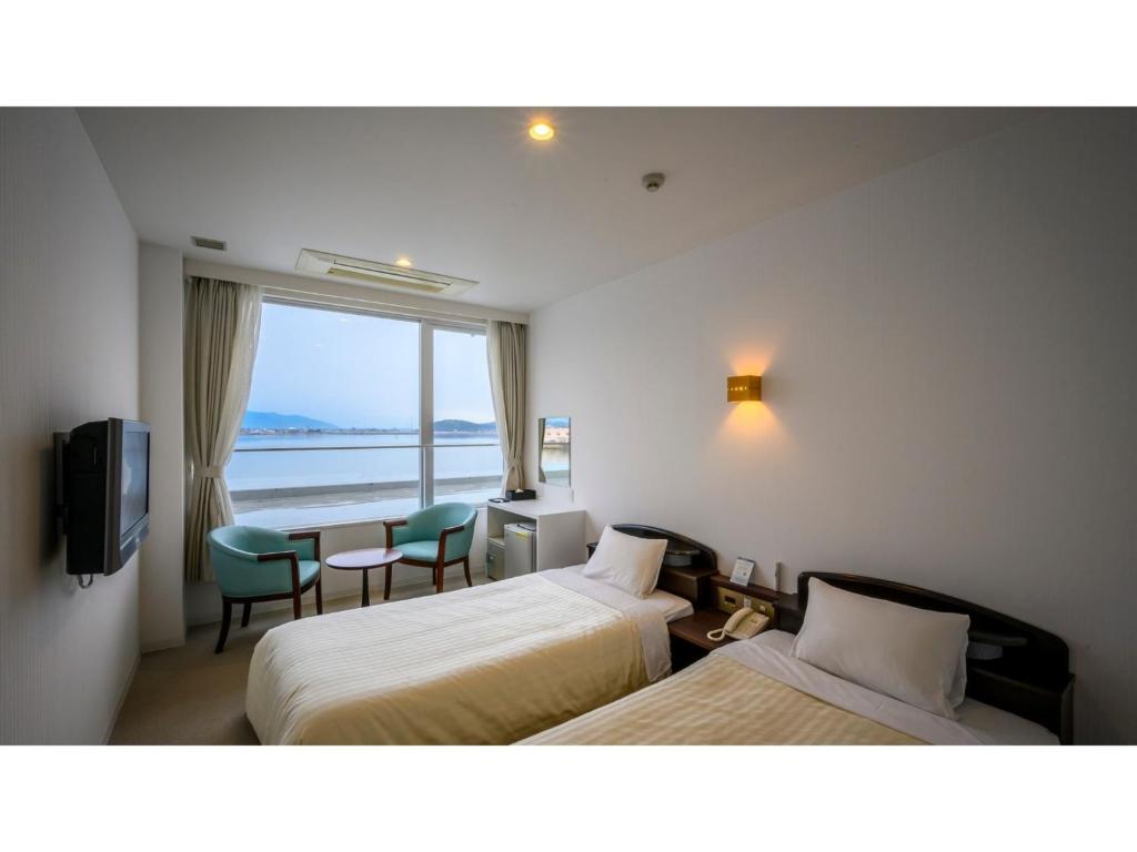 出雲市にあるKohan no Onsen Yado Kunibiki - Vacation STAY 35288vのベッド2台が備わる海の景色を望むホテルルームです。