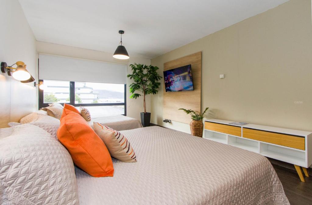 een slaapkamer met een bed met oranje kussens bij Rivadavia Apartamentos in Ushuaia