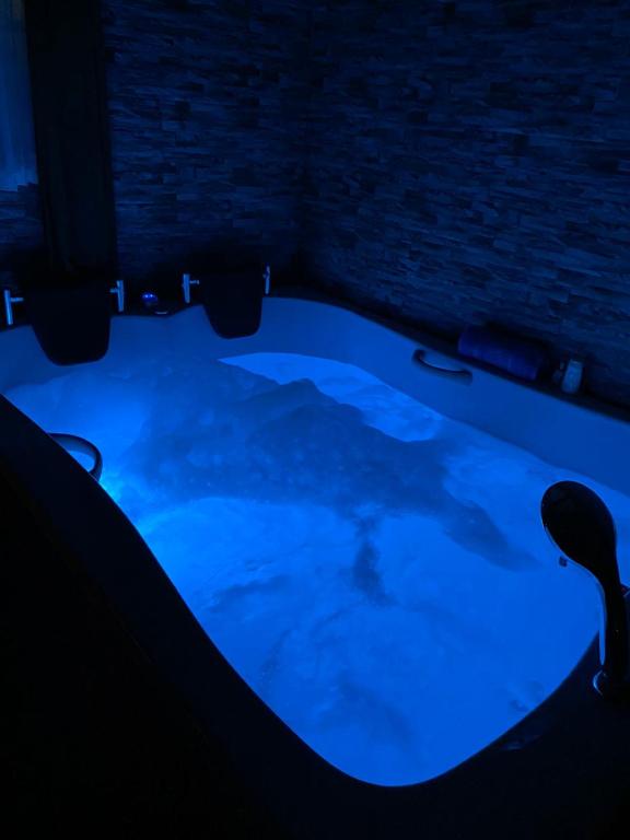 bañera de hidromasaje en una habitación oscura con iluminación azul en Zennat bungalov, 