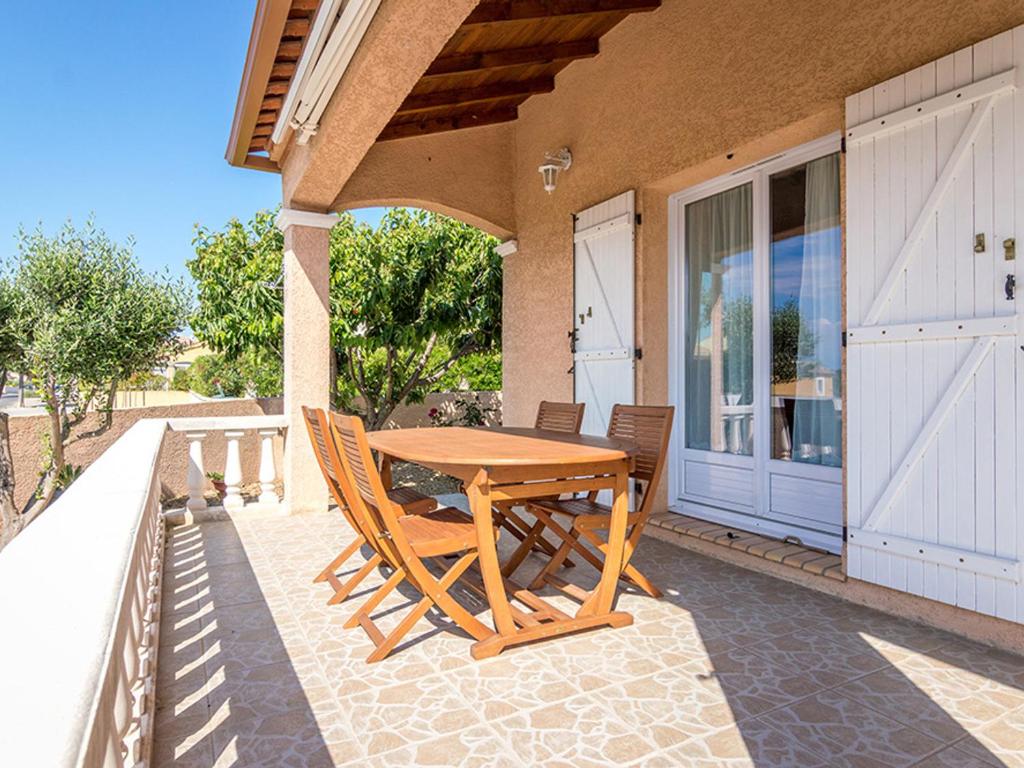 une table et des chaises en bois sur une terrasse dans l'établissement Maison de plain-pied avec jardin, clim, 3 chambres et parking près du Bassin de Thau - FR-1-604-19, à Mèze