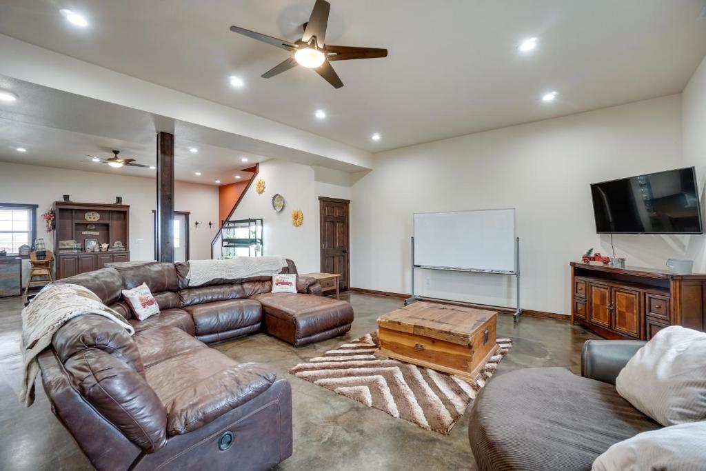 sala de estar con sofás de cuero y pantalla en Pet-Friendly Lingle Ranch with Deck on 60 Acres! 