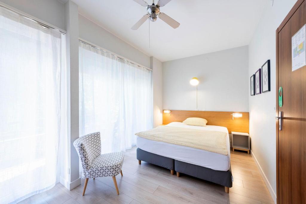 a bedroom with a bed and a chair and a window at Hotel Atlantico in Lugano