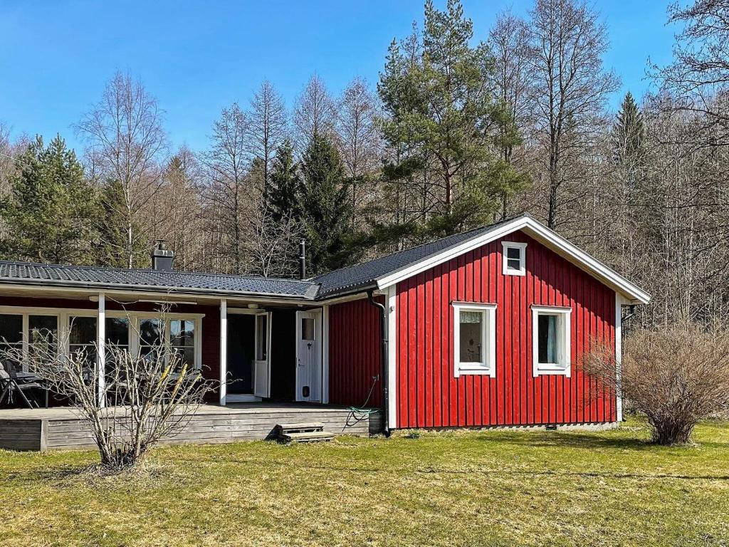 una casa roja con una puerta blanca en un patio en Lakefront Cottage in Torsebo, en Askersund