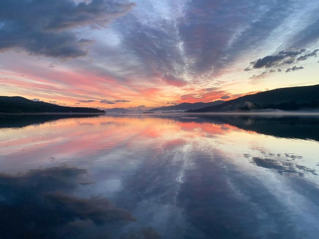 a large body of water with a sunset in the background at Depe Dene Lakeside Resort in Lake George