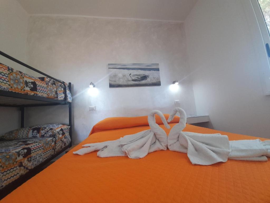 una cama naranja con dos cisnes hechos de toallas en Vulcano: La Porta Delle Eolie, en Vulcano