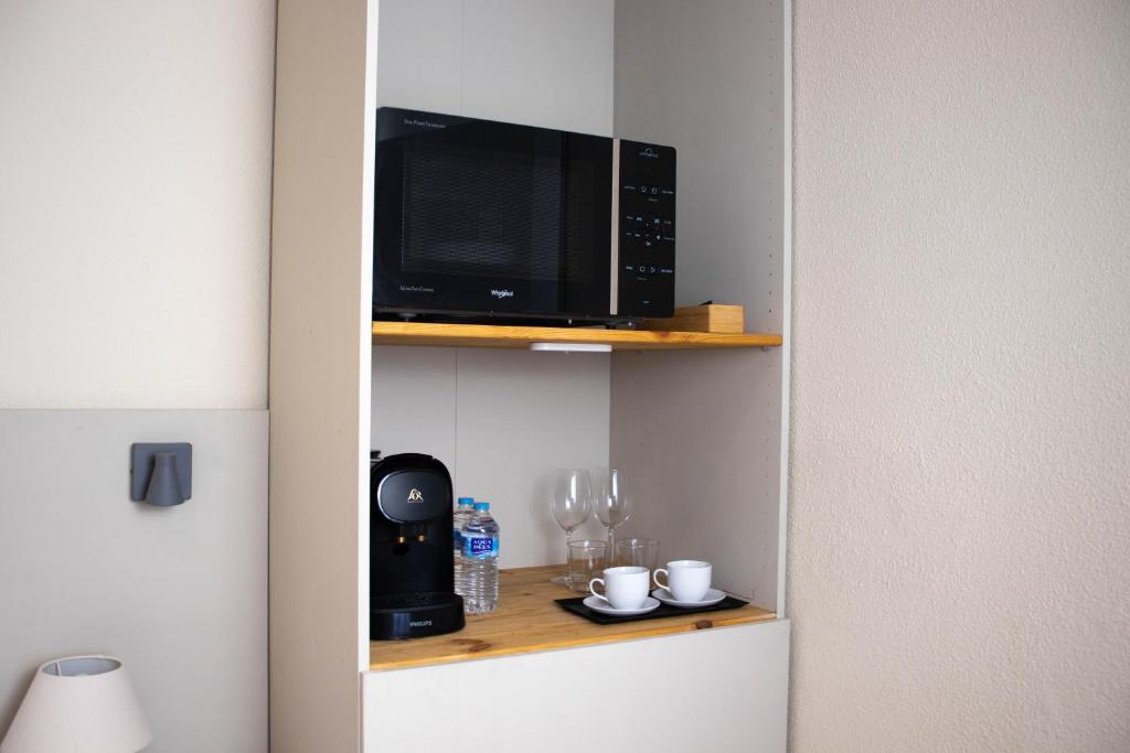 a microwave oven sitting on a shelf next to a table at Apartamentos Centro in Albacete