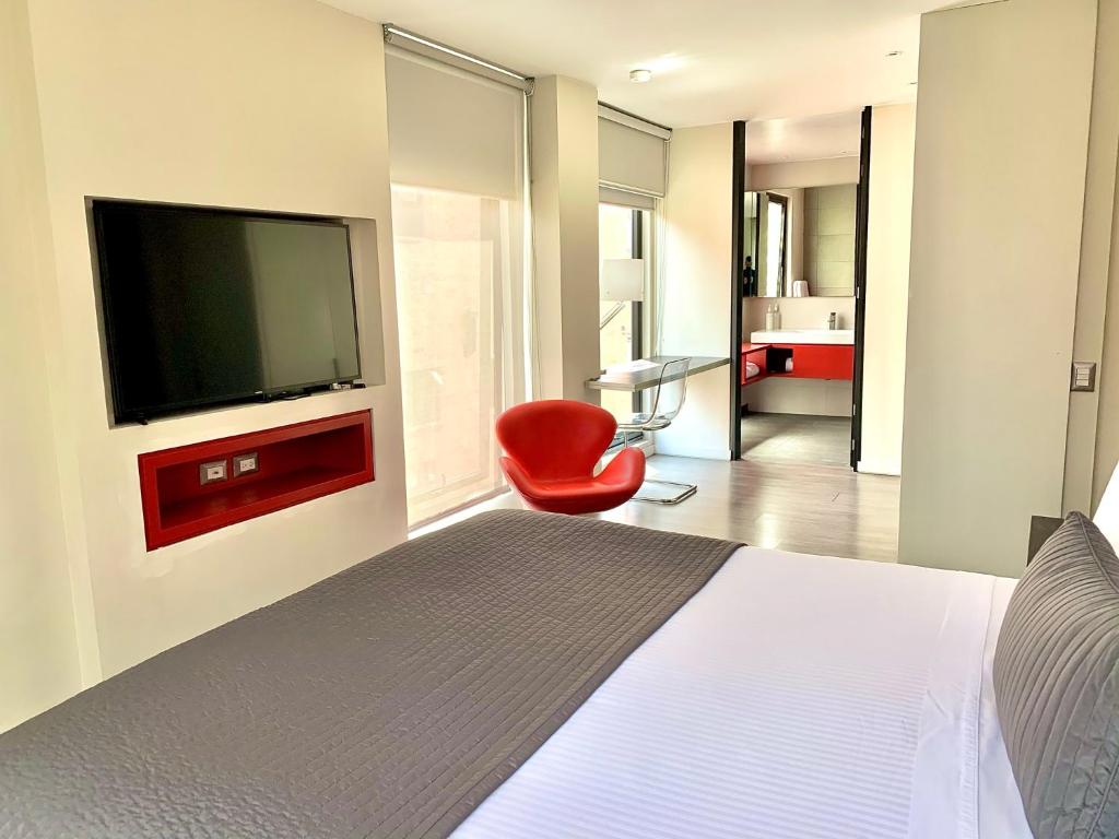 a bedroom with a bed with a television and a red chair at Central Apartamentos Bogotá in Bogotá