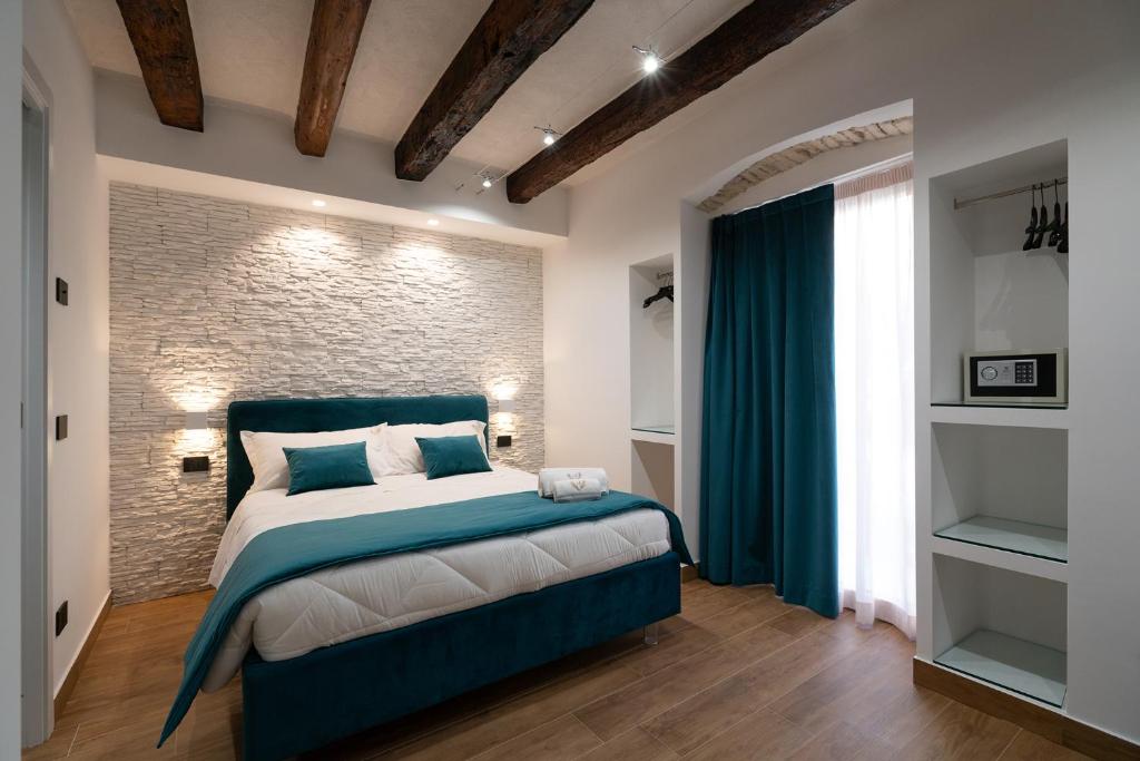 a bedroom with a blue bed and a brick wall at Sofi' Center Rooms in Sciacca