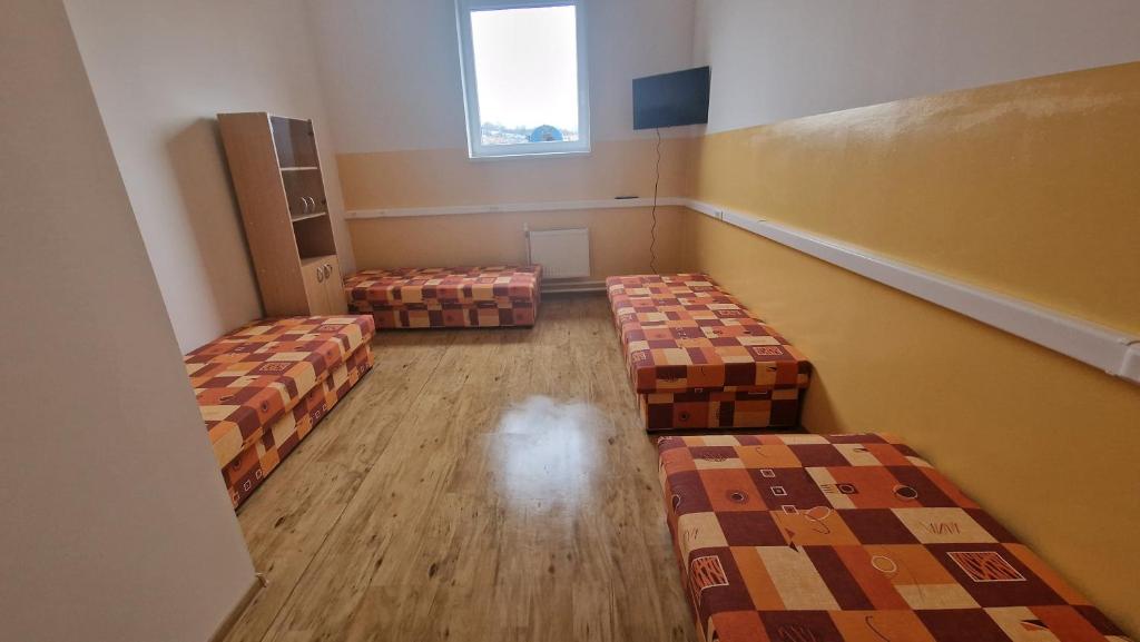 an empty room with three beds and a window at Privat Prešov in Prešov