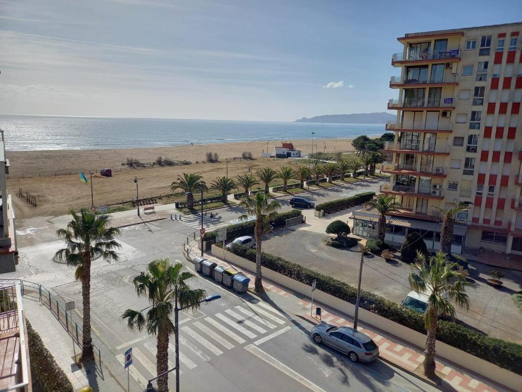 una calle con palmeras, un edificio y la playa en Rocamaura B 5/4, en L'Estartit