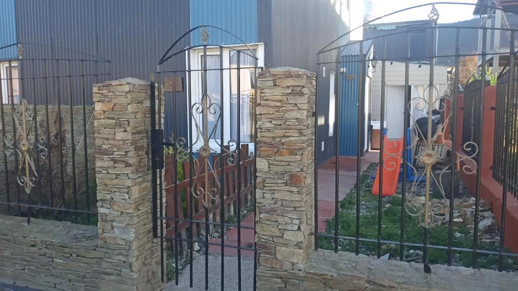 une clôture en fer forgé avec piliers en pierre devant un bâtiment dans l'établissement Shabat, à Ushuaia
