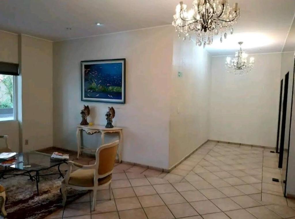 a living room with a table and a chandelier at Apartamento Aconchegante SETOR OESTE in Goiânia