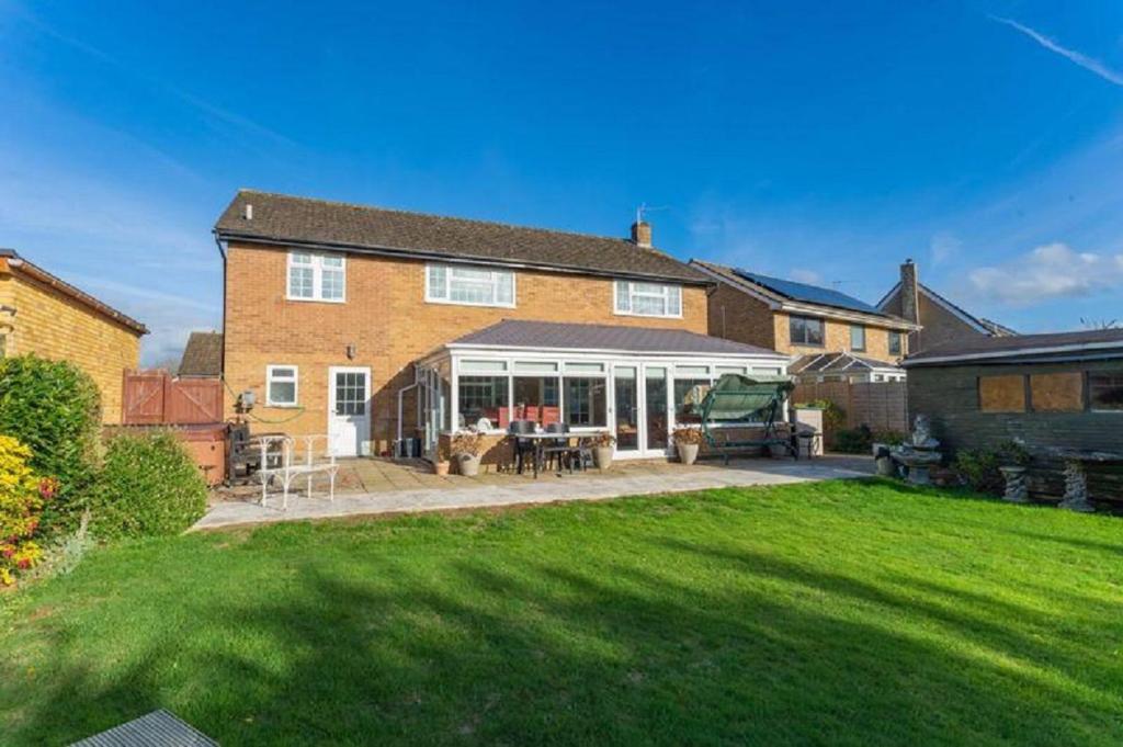 a large brick house with a patio and a yard at Kennedy Villa - 5 Bed House with Hot Tub in Bicester