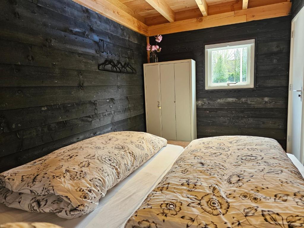 een slaapkamer met 2 bedden en een houten muur bij Ham Annex met privé jacuzzi in Almelo