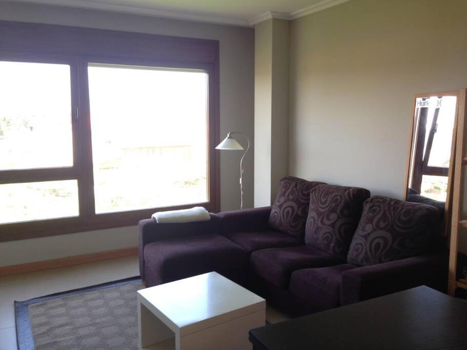 ein Wohnzimmer mit einem lila Sofa und 2 Fenstern in der Unterkunft Apartamento acogedor en la playa de La Lanzada in Sanxenxo
