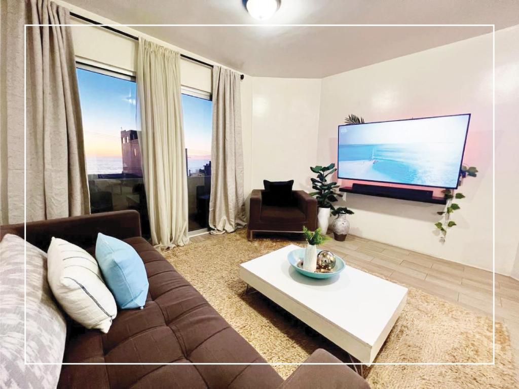 sala de estar con sofá y TV de pantalla plana en Condominio completo con vista al mar, en Tijuana