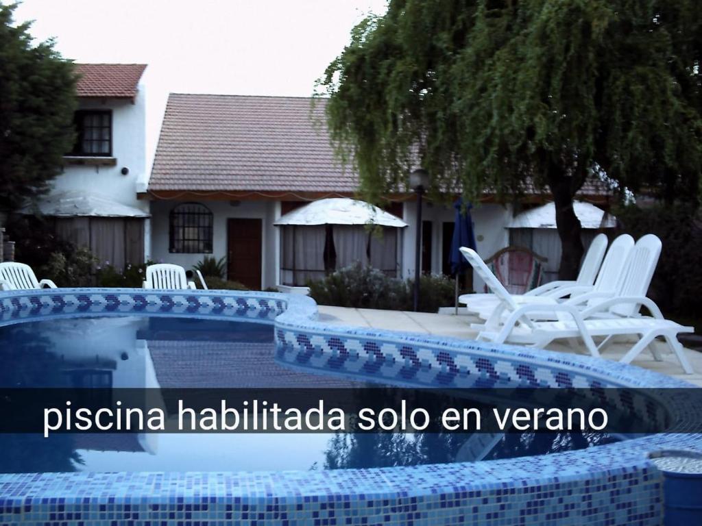 a pool with white chairs in front of a house at Complejo Tehuelches in Puerto Madryn