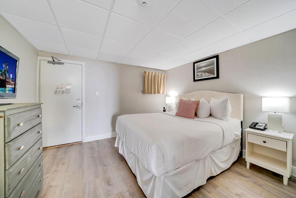 a bedroom with a large white bed and a dresser at Montreal Beach Resort in Cape May