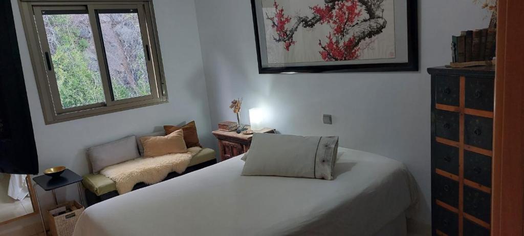 a bedroom with a bed and a chair and a window at Cozy room near Las Teresitas beach in Santa Cruz de Tenerife