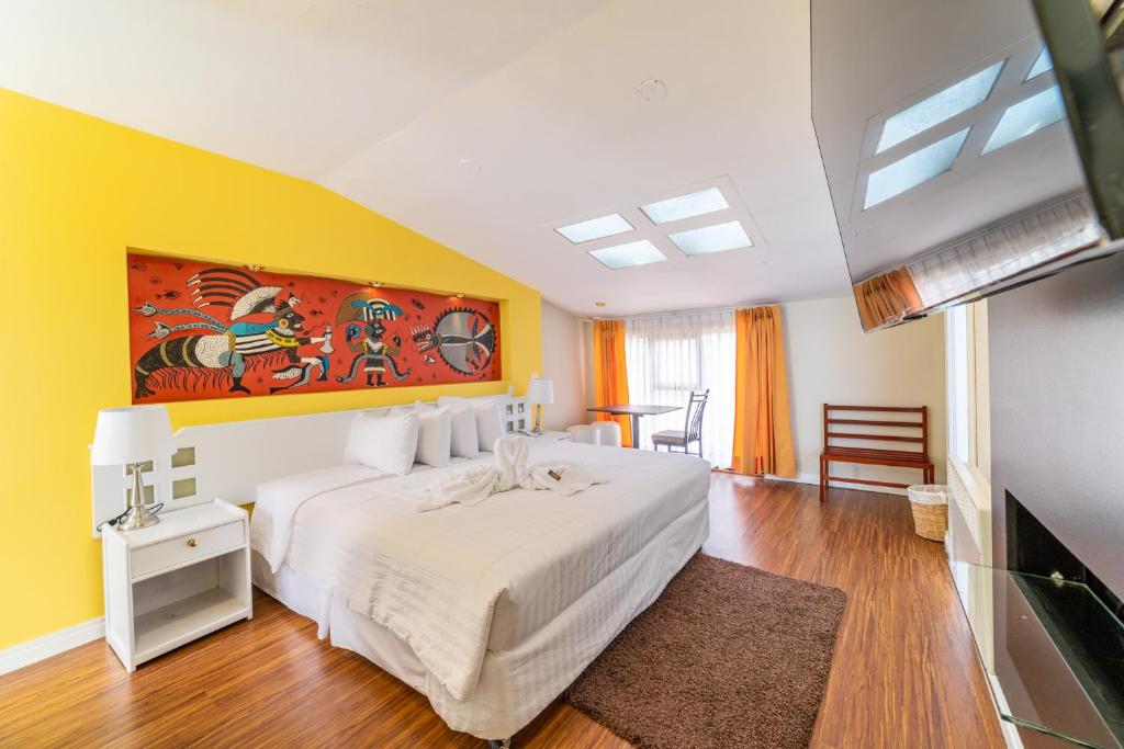 a bedroom with a white bed and a yellow wall at Hotel Qalasaya in Puno