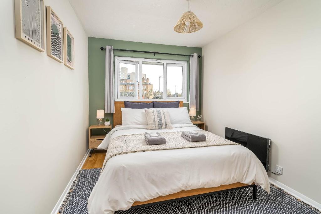 um quarto com uma cama grande e uma janela em Homely and Stylish Bermondsey Apartment with Parking em Londres