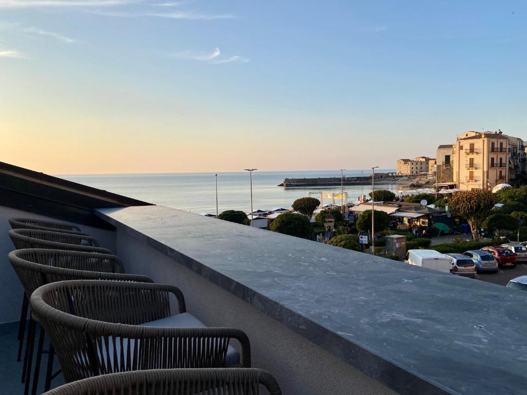 una fila di sedie su un balcone con vista sull'oceano di Salemare Rooms & Suites a Cefalù