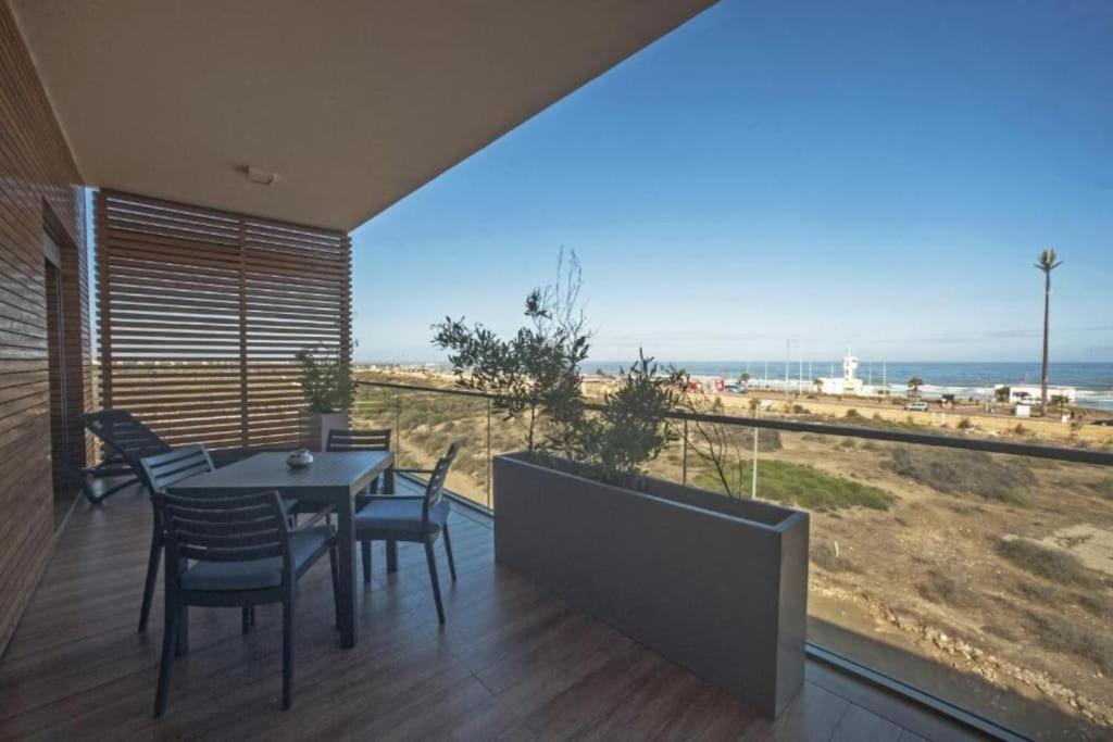 a table and chairs on a balcony with a view of the beach at Luxury Apartment at Corniche , Seaview Close Beach in Casablanca