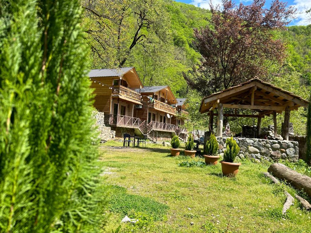 Cottages in mountains في K'veda Bzubzu: كابينة خشب بها ساحة بها نباتات ومبنى