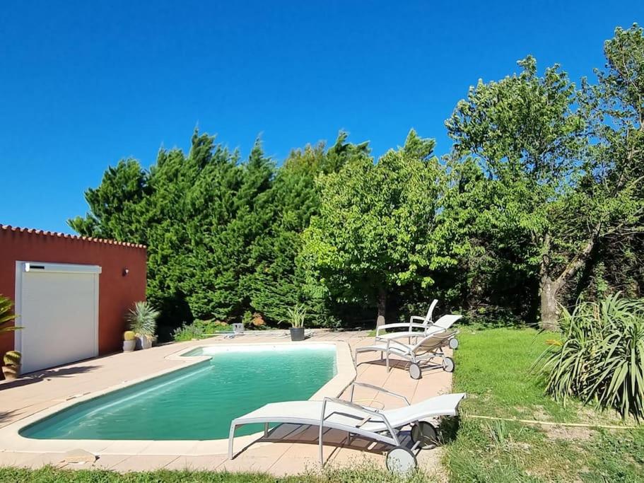 einen Pool mit Stühlen neben einem Hof in der Unterkunft villa avec studio indépendant et piscine in Jonquières