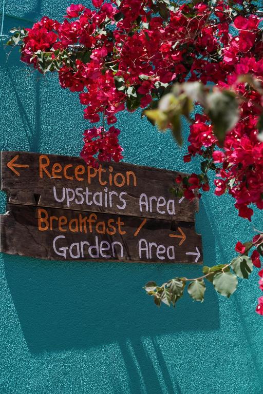 a wooden sign on a wall with red flowers at Natural Mystic Hostel in Costa da Caparica